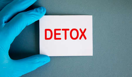 Hand in blue glove with white card. Concept word detox.の写真素材
