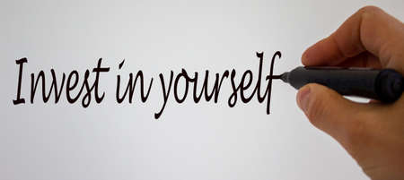 Hand writing 'invest in yourself', isolated on white background.の写真素材