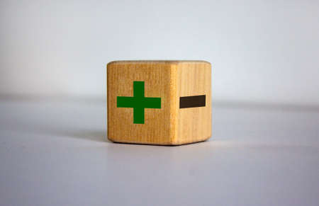 The concept of opposites, wood blog with plus and minus on blue background, flat lay, copy space.の写真素材