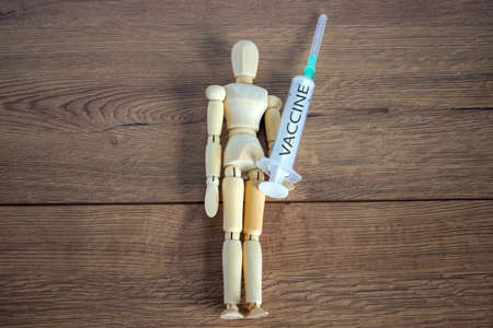 COVID-19 Pandemic Coronavirus concept ; Wooden model of a man holding a syringe labeled vaccine.の写真素材