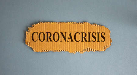 Word coronacrisis on the piece of cardboard on blue fon.の写真素材