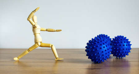 COVID-19 Pandemic Coronavirus concept ; Wooden model of a man human model fights against abstract models of coronovirus.の写真素材