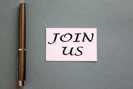 Pen and white card with words 'join us' on blue background.の写真素材