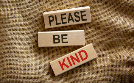 Wooden blocks form the text 'please be kind' on beautiful canvas background.の写真素材