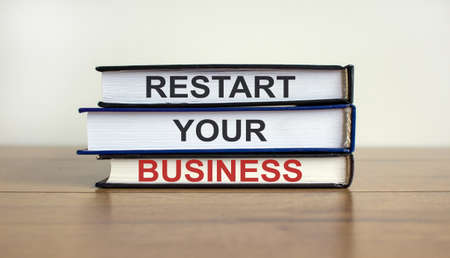 Books with text 'restart your business' on beautiful wooden table. White background. Business concept.の写真素材