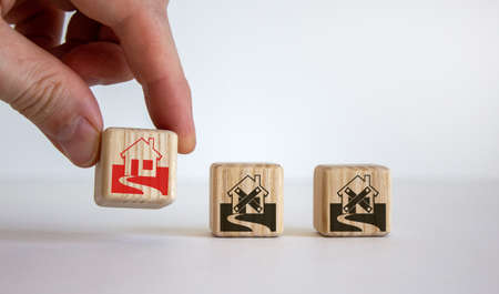 Male hand placing a cube with house sign near of a other cubes. Cubes with abandoned house icons....