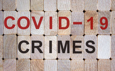 Wooden blocks form the words 'covid-19 crimes'. Beautiful wooden background.の写真素材