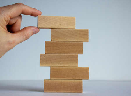 Concept of building success foundation. Women hand put wooden blocks on the stack of wooden blocks.の写真素材