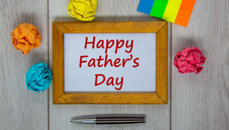 Wooden frame with inscription 'Happy Father's Day' on beautiful wooden table, colored paper, metalic pen. Concept.の写真素材