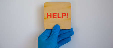 COVID-19 Pandemic Coronavirus concept.The doctor holds in his hand a tablet saying help. Gloved hand.の写真素材
