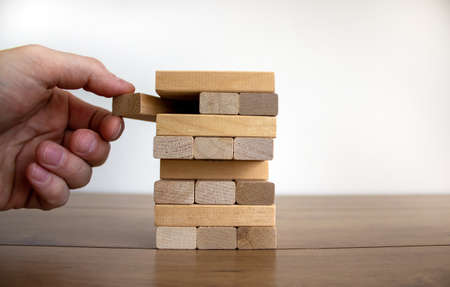 Male hand draws a block from the model of business, made from wood blocks. Alternative risk concept, business plan and business strategy. Insurance concept. White background, copy space.の写真素材