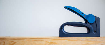 A construction stapler on a wooden bar. Beautiful white background. Copy space.の写真素材