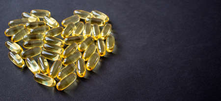 Yellow pills in the shape of a heart on a dark backgroundの写真素材