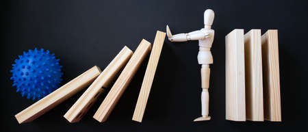 COVID-19 Pandemic Coronavirus concept. Wooden model of man stopping wooden domino blocks.の写真素材