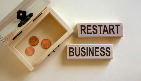 Concept words 'restart business' on blocks on a beautiful white background, small chest with coins. Beautiful white background, copy space.の写真素材