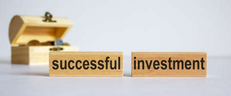 Concept words successful investment on blocks on a beautiful white background, small chest with coins.の写真素材