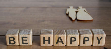 Be Happy letters cubes on wooden floor. Wooden figures of man and woman.の写真素材