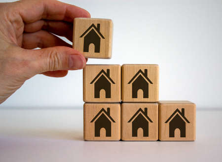 Male hand placing a house cube on top of a pyramid. Beautiful white background. Business concept.の写真素材