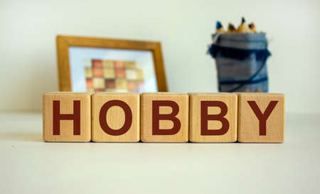Wooden cubes with the inscription 'hobby'. Frame with a picture and a bag with pencils in the background. Beautiful white background, copy space.の写真素材