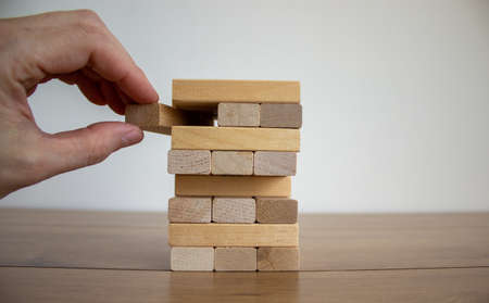 Male hand draws a block from the model of business, made from wood blocks. Alternative risk concept, business plan and business strategy. Insurance concept. White background, copy space.の写真素材