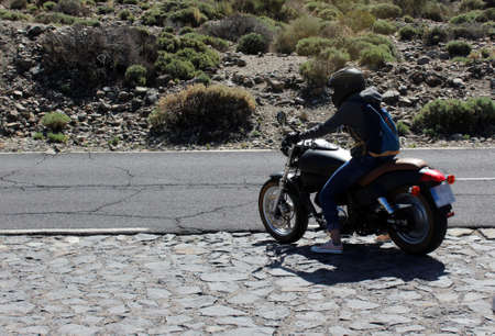 Motorcyclist girl on a motorcycle goes on a road. Tenerife, Spain.の写真素材