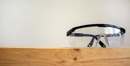Safety glasses on a wooden bar. Beautiful white background. Copy space.の写真素材