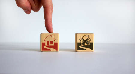Hand making a choice between two cubes with house icon on beautiful white background. Business and crisis recovery concept.の写真素材