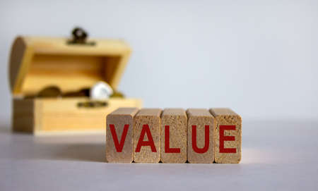 Concept word 'value' on wooden blocks on a beautiful white background, small chest with coins.の写真素材