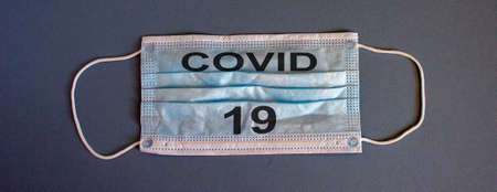 blue medical protective mask on a gray background with inscription Covid-19, concept accessory for coronavirus protectionの写真素材