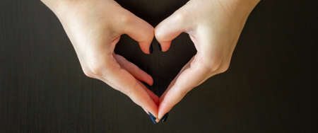 Girl hand in heart form love on dark background