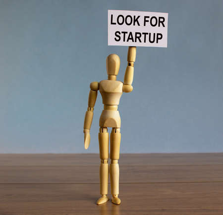 Wooden model of a man holding a tablet saying 'look for startup'.の写真素材