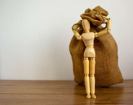 Wooden model of a human near large canvas bag.の写真素材