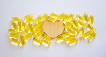 Gelatinous capsules with the cod-liver oil-omega3 on white background. Wooden hearts. Web banner with a copy space.の写真素材