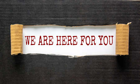 The words 'we are here for you' appearing behind torn black paper. Beautiful background. Business concept.の写真素材