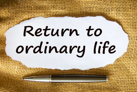 The text 'return to odinary life' on white paper. Metalic pen. Beautiful canvas background. Business concept.の写真素材