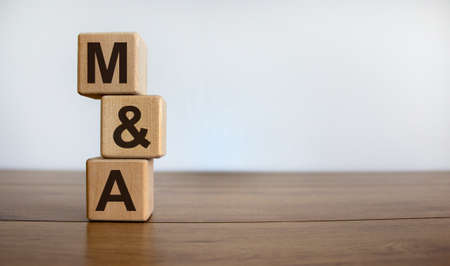 Concept word 'M&A' on cubes on a beautiful wooden table. White background. Business concept. Copy space.の写真素材