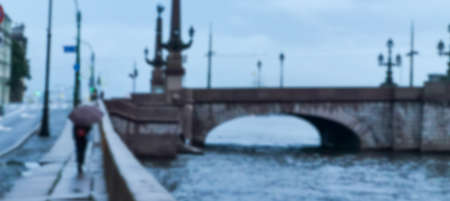 People under umbrellas on a city bridge. Blurred image.の写真素材