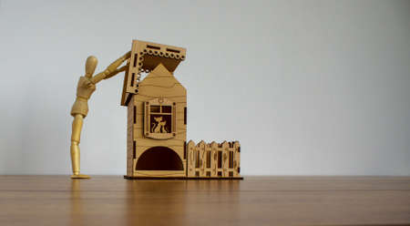 Wooden man builds a model of a wooden house. Place for your text.の写真素材