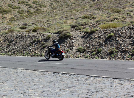 Motorcyclist girl on a motorcycle goes on a road. Tenerife, Spain.の写真素材