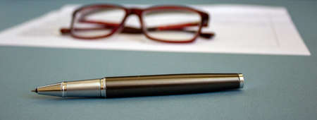 Glasses and pen on white documentの写真素材