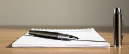 White notebook pen and cap on beautiful wood table. Warm sunlight.の写真素材