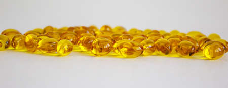 Yellow vitamins tablets, fish oil, Omega Vitamin E. Pills on a white background. Web banner with a...
