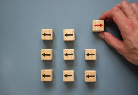Individuality conceptual image. Male hand with wooden cubes on beautiful blue background.