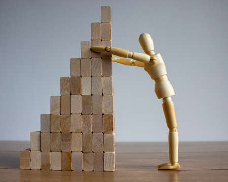 Wooden model of human put wooden blocks on the stack of wooden blocks. Concept of building success foundation.の写真素材