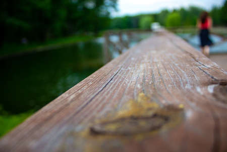 Old wooden board close-up. In the background a blurred lake and the silhouette of a young girl.の写真素材