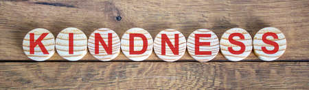 The word 'kindness' on wooden circles on wooden table. Beautiful background, copy space.