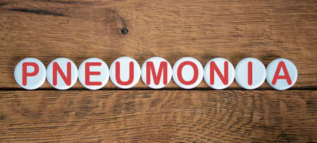 COVID-19 Pandemic Coronavirus concept. Wooden circles with the inscription pneumonia.の写真素材