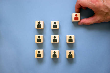 Individuality conceptual image. Male hand with wooden cubes on beautiful blue background.の写真素材
