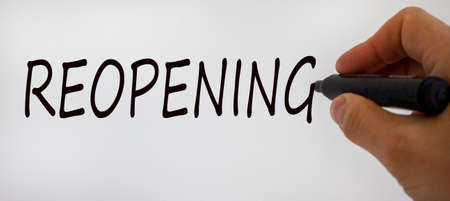 Hand writing 'reopening', isolated on beautiful white background. Concept.の写真素材