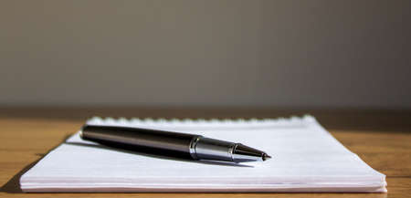 White notebook and pen on beautiful wood table. Warm sunlight. Business concept.の写真素材